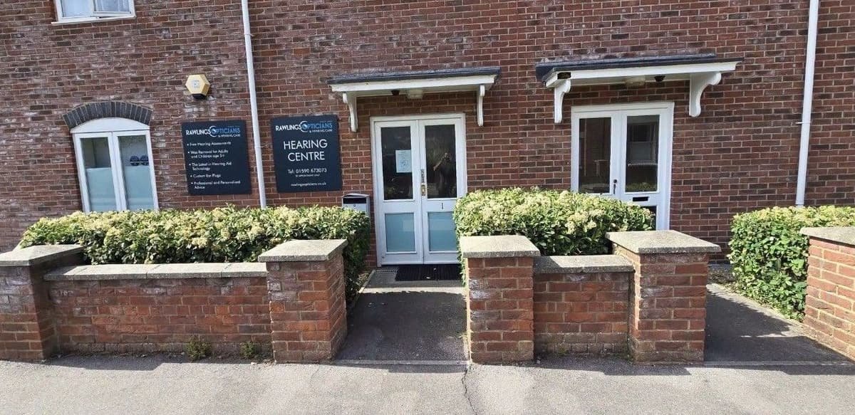 Shrubs in front of a business entrance trimmed back below the wall line, clearing the doorway