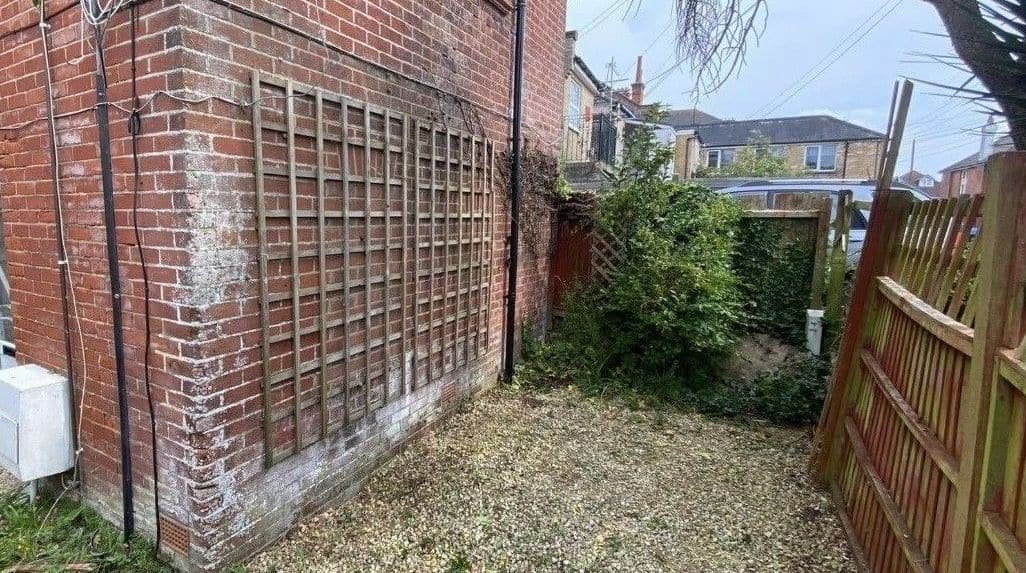 Side passage with climbing overgrowth removed from the brickwork and gravel cleared