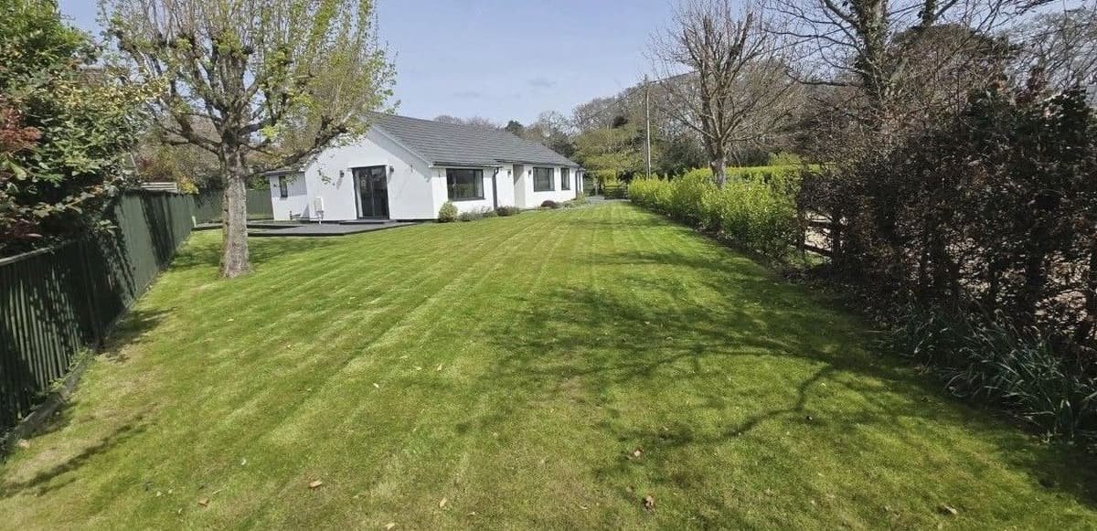 Long striped lawn in front of a white bungalow, freshly mown